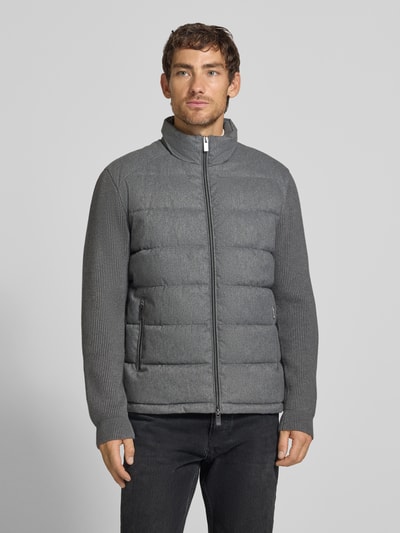 Männermodel trägt Steppjacke mit Stehkragen und Zweiwege-Reißverschluss von Christian Berg Men in Grau, Regular Fit, Ganzkörperansicht von vorne. Rückenlänge 70 cm, Schulterbreite 51 cm, Brustweite 60 cm, Ärmellänge 69 cm.