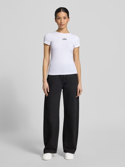 Frauenmodel trägt T-Shirt in Ripp-Optik mit Logo von GAP, weiß, Slim-Fit, Baumwoll-Mix mit Modal-Anteil, Rundhalsausschnitt, Rückenlänge 53 cm, Ganzkörperansicht von vorne.