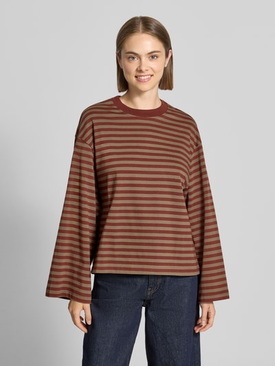 Modelka nosi Relaxed Fit bluzka z długim rękawem z czystej bawełny od Gina Tricot w paski, okrągły dekolt, długość tyłu 62 cm, rozmiar S, kolor brązowy i beżowy, faktura gładka, krój relaxed fit, widok na całe ciało z przodu.
