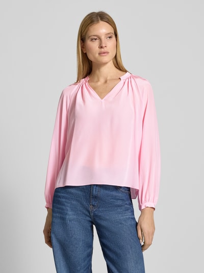 Vrouwenmodel draagt Regular Fit Bluse mit V-Ausschnitt van HERZENS in lichtroze, vloeiende stof, tuniekkraag, voorkant, borst-opname.