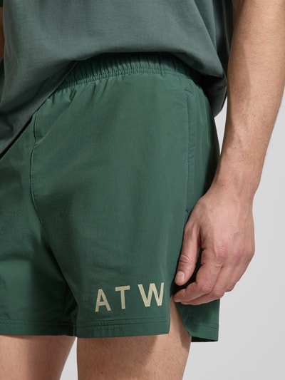 Männermodel trägt Shorts mit elastischem Bund von HALO in Dunkelgrün, Regular-Fit, Material-Mix mit Stretch-Anteil, Label-Print, Nahaufnahme Oberkörper.