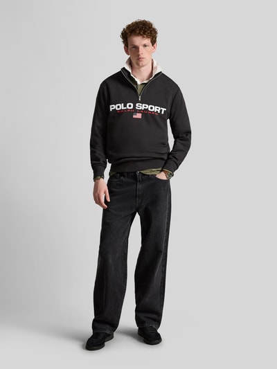 Männermodel trägt schwarzen Relaxed Fit Troyer aus Baumwoll-Mix von Polo Ralph Lauren, rote und weiße Schrift, Ganzkörperansicht von vorne. Herren Troyer von Polo Ralph Lauren