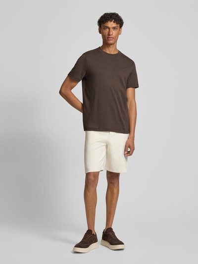 Männermodel trägt T-Shirt mit Logo-Stitching Modell 'Priamo' von JOOP! Collection in Braun, reine Baumwolle, gerader Schnitt, Ganzkörperansicht von vorne.