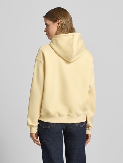 Vrouwenmodel draagt Regular Fit Hoodie met kangoeroezak model 'Iconic' van Gina Tricot, katoenmix, dames, regular fit, elastische boorden. Ganzebodyachteraanzicht.