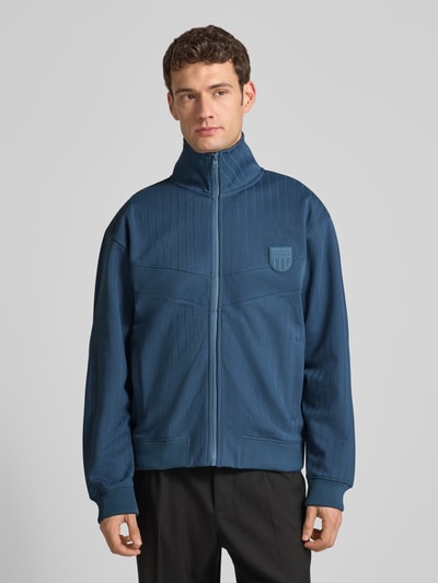 Männermodel trägt Regular Fit Sweatjacke aus Baumwoll-Mix Modell 'DAVRONTO' von HUGO, blau, gestreift, Label-Patch, Ganzkörperansicht von vorne.