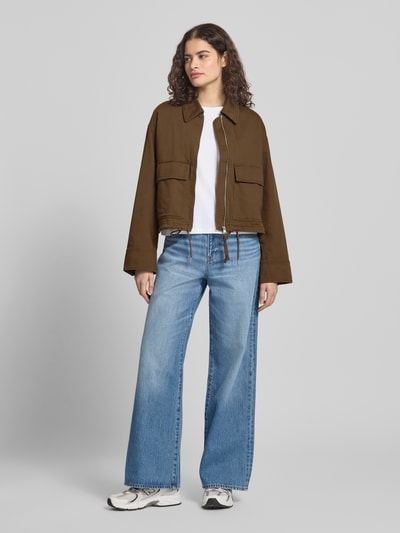 Kobiece model prezentuje Regular Fit Jeansjacke aus Baumwoll-Mix von Marc O'Polo Denim, efekt: jednolity kolor, krój regular fit, wykładany kołnierz, zamek błyskawiczny, naszywka z logo, długi rękaw, mankiety zapinane na zatrzaski, kieszenie na piersi, wykończenie materiału: denim, mieszanka bawełny, widok całej sylwetki z przodu.