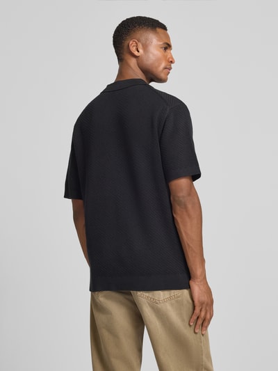 Männermodel trägt schwarzes Regular Fit Poloshirt mit Label-Detail Modell 'ISAKSSON' von Casual Friday, reine Baumwolle, Rückenansicht Ganzkörperansicht.