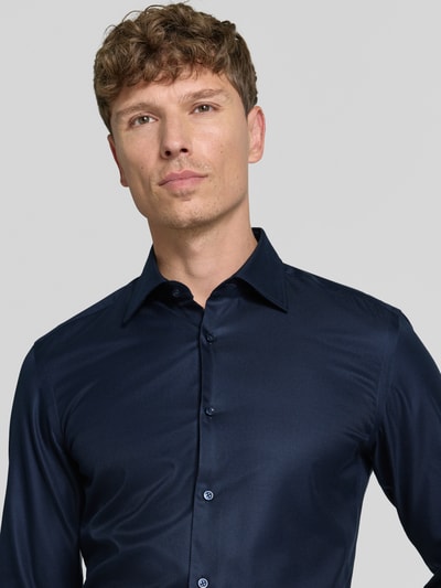 Männermodel trägt dunkelblaues Slim-Fit Businesshemd aus Baumwolle Modell 'H-HANK-K' von BOSS, Nahaufnahme Oberkörper.