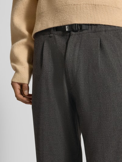 Männermodel trägt Tapered Bundfaltenhose mit Viskose-Anteil von Marc O'Polo Denim in Melange-Optik mit Gürtel und seitlichen Eingrifftaschen, Nahaufnahme Oberkörper.