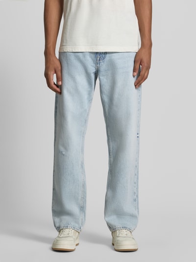 Männermodel trägt Straight Fit Jeans im 5-Pocket-Design Modell 'Damon' von Guess in Hellblau mit glatter Textur, Ganzkörperansicht von vorne, reine Baumwolle