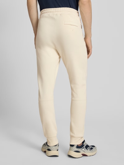 Männermodel trägt Regular Fit Sweatpants mit Label-Applikation von Balr., beigefarbener Baumwoll-Mix, Ganzkörperansicht Rückansicht.
