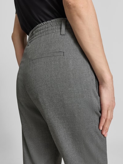 Kobieta nosi Stoffhose mit Gesäßtaschen Modell 'DISPATCH' od Drykorn, szary odcień, krój regular fit, detal z tyłu, materiał z domieszką wiskozy, szerokość w rozmiarze 27/34: 40 cm, długość wewnętrzna nogawki: 67 cm, zdjęcie detaliczne tylnej części.