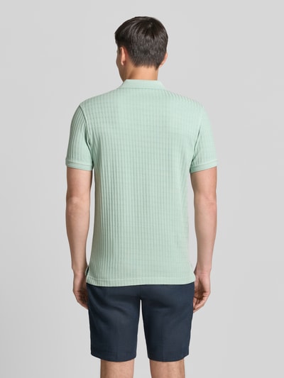 Männermodel trägt Slim Fit Poloshirt mit Logo-Stitching von Lerros aus Baumwoll-Mix in Hellgrün, Rückenlänge 74 cm, Ganzkörperansicht Rückansicht.
