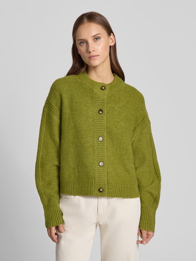 Frauenmodel trägt Boxy Fit Strickjacke Modell 'FLORA' von Topshop, grün, Rundhalsausschnitt, Knopfleiste, Strukturstrick, Ganzkörperansicht von vorne. Damen Strickjacke, Rückenlänge 54 cm, Ärmellänge 53 cm.
