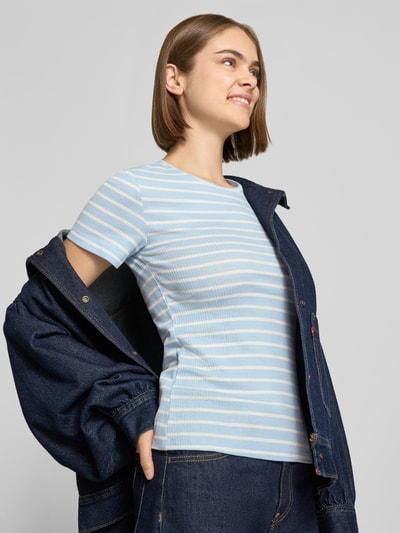 Vrouwenmodel draagt Slim Fit T-Shirt uit katoenmix Model 'RUKA' van Pieces, gestreept motief in lichtblauw en wit, fijnrib, korte mouw, ronde hals, all-over motief, effen kleuren, Ganzkörperansicht van voren.
