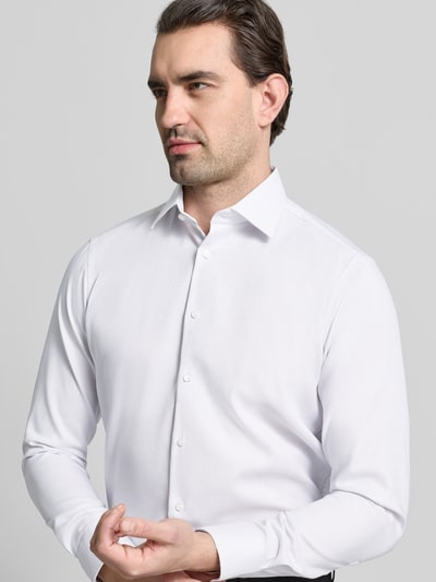 Męski model nosi Regular Fit Business Hemd aus Baumwolle mit Kentkragen von Christian Berg Men, biała, gładka tkanina, krój regular fit, Kent kołnierzyk, listwa guzikowa, długość pleców w rozmiarze 39/40: 78 cm, szerokość ramion w rozmiarze 39/40: 47 cm, długość rękawa w rozmiarze 39/40: 64 cm, widok na górną część sylwetki z przodu