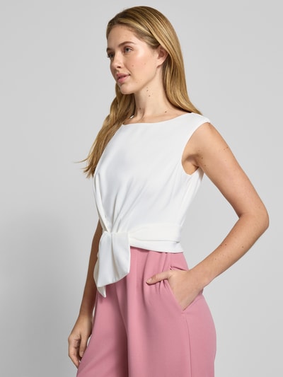 Modelka nosi Kombinezon mit Knotendetail von Vera Mont, mieszanka materiałów z dodatkiem streczu, krój regular fit, okrągły dekolt, wiązany detal, długość tyłu w rozmiarze 36: 39 cm, szerokość w rozmiarze 36: 30 cm, całkowita długość w rozmiarze 36: 150 cm, długość wewnętrzna nogawki w rozmiarze 36: 83 cm, jasnobiałe i pasteloworóżowe kolory, tkanina gładka; ujęcie całej sylwetki z przodu.