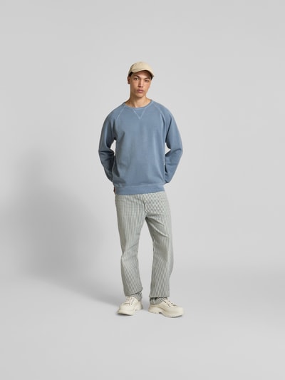 Männermodel trägt Relaxed Fit Sweatshirt aus Baumwolle von Closed in Blau mit Raglanärmel, Rundhalsausschnitt und elastischen Abschlüssen, Ganzkörperansicht von vorne.
