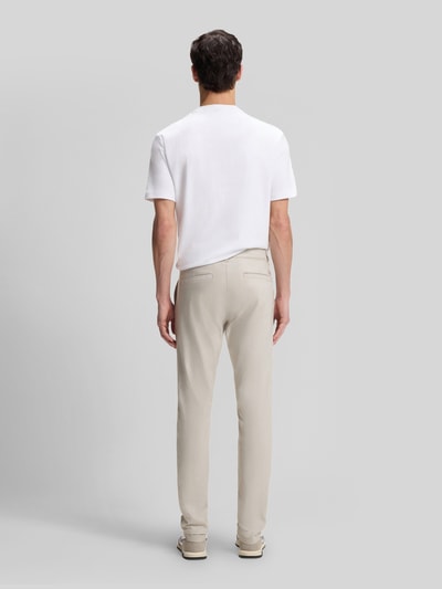 Männermodel trägt Slim Fit Chino aus Baumwoll-Mix mit Leinen und Viskose-Anteil von BOSS Orange in heller Denim-Optik, Ganzkörperansicht Rückansicht. Passform: Slim-Fit, Materialverarbeitung: Twill, Label-Patch, Label-Applikation, Mid Waist, Knopf und verdeckter Reißverschluss, seitliche Eingrifftaschen, Gesäßtaschen.