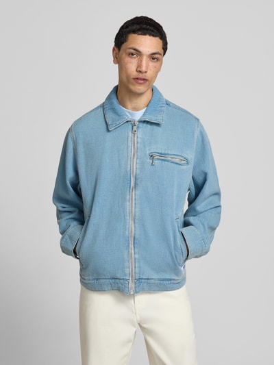 Męski model nosi Regular Fit Jeansjacke aus reiner Baumwolle Modell 'ELZO' od HUGO Blue, jasnoniebieski denim, prosty krój regular fit, zamek błyskawiczny, długie rękawy, kieszenie boczne, materiał: czysta bawełna, tekstura tkaniny, Ganzkörperansicht von vorne.