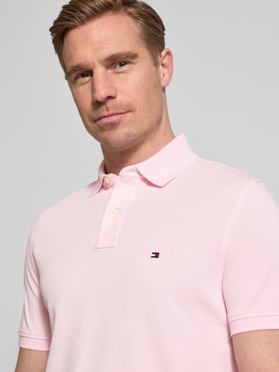 Männermodel trägt Regular Fit Poloshirt aus Baumwoll-Mix von Tommy Hilfiger, efekt: jednolity kolor, krótki rękaw, wyhaftowane logo, kołnierzyk polo, zapięcie na 2 guziki, pika, mieszanka bawełny, nahaufnahme górnej części ciała.
