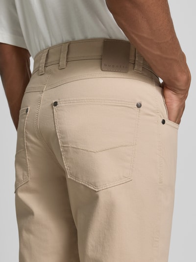 Männermodel trägt Regular Fit Hose mit Eingrifftaschen Modell 'CORDOBA' von bugatti, beiger Baumwoll-Elasthan-Mix, Nahaufnahme Rückansicht.