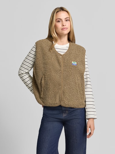 Frauenmodel trägt Regular Fit Weste aus Teddyfell Modell 'Hoktown' von American Vintage, beige, mit Logo-Patch und Knopfleiste, Ganzkörperansicht von vorne, Damen Weste aus Teddyfell, lockere Passform, strukturierte, flauschige Textur, Kontext: Rückenlänge 57 cm, Schulterbreite 43 cm, Brustweite 63 cm.
