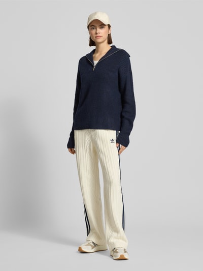 Vrouwenmodel draagt Loose Fit Strickhose uit viscosemix van adidas Originals met elastische band, logostitching, galonstrepen, Ganzkörperansicht van voren.