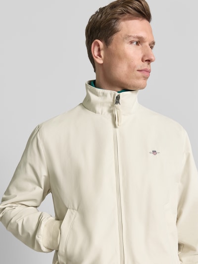 Männermodel trägt Jacke mit Stehkragen und Zweiwege-Reißverschluss von Gant in Creme, Material-Mix, Regular-Fit, Label-Stitching, Nahaufnahme Oberkörper.