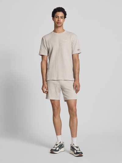 Mężczyznamodel nosi Shorts mit Strukturmuster und elastischem Bund von CHAMPION, bawełniany miks, krój regular fit, wzór strukturalny, label-stitching, elastyczny pas, szerokość w rozmiarze M: 40 cm, długość wewnętrzna nogawki w rozmiarze M: 19 cm, jasny beż, gładka tekstura, całościowe ujęcie z przodu.