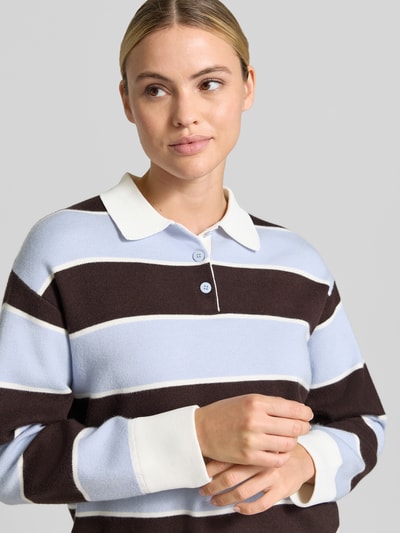 Frauenmodel trägt Regular Fit Poloshirt aus Viskose-Mix von MANGO, breite Streifen in Braun und Hellblau, Nahaufnahme Oberkörper. Damen Poloshirt, Viskose-Mix, Polokragen, elastische Ärmelabschlüsse, langärmelig.