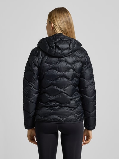 Frauenmodel trägt schwarze Steppjacke mit Daunen-Federn-Füllung Modell 'Helium' von PEAK PERFORMANCE, Regular Fit, Ganzkörperansicht Rückansicht.