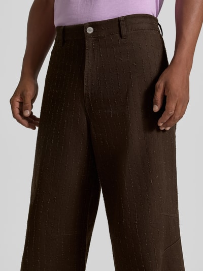 Mannelijk model draagt Wide Fit Jeans uit puur katoen van Samsøe Samsøe met structuurpatroon, knoop- en ritssluiting, achterzakken, donkerbruin, bandwijdte maat 50: 45 cm, binnenbeenlengte maat 50: 80 cm, detailopname voortaan.