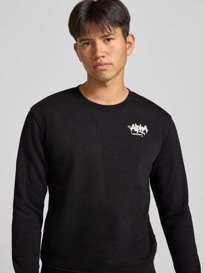 Männermodel trägt Regular Fit Sweatshirt aus Baumwoll-Mix von Alpha Industries mit Logo-Print, Schwarz, Nahaufnahme Oberkörper.