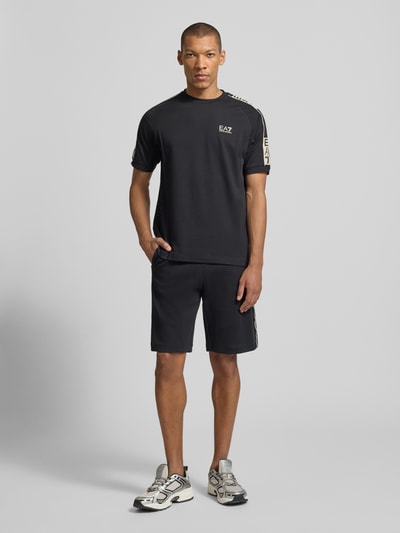 Männermodel trägt schwarze Shorts mit elastischem Bund von EA7 Emporio Armani, Baumwoll-Mix, Regular Fit, Ganzkörperansicht von vorne.