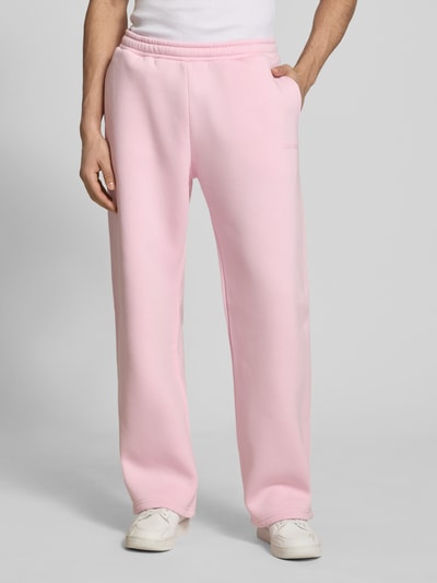 Männermodel trägt Sweatpants mit elastischem Bund von REVIEW in Rosa, Relaxed-Fit, Material-Mix mit Baumwoll-Anteil, Gesäßtasche, Ganzkörperansicht von vorne.