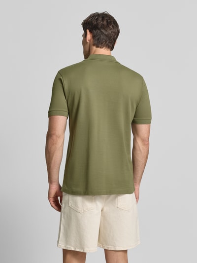 Männermodel trägt Regular fit poloshirt aus puur katoen van Lacoste in olijfgroen, gecombineerd met lichte shorts, Ganzkörperansicht Rückansicht. Heren poloshirt van Lacoste.