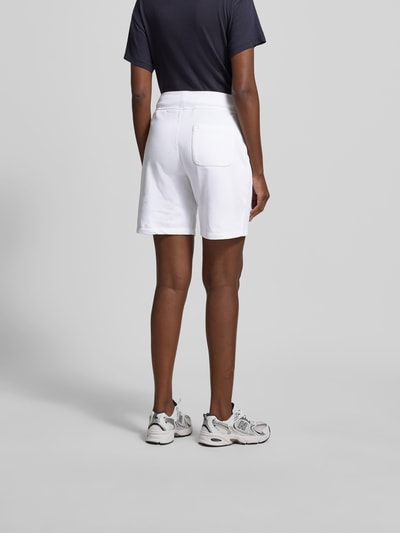 Frauenmodel trägt Sweatshorts aus Baumwoll-Mix von Juvia in Weiß mit breitem Bund, Eingrifftaschen, gerader Passform, Ganzkörperansicht Rückansicht.