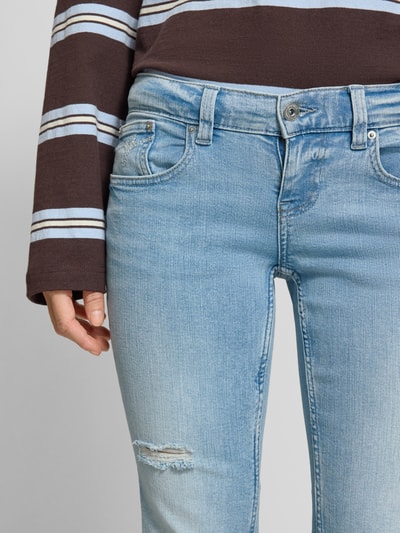 Frauenmodel trägt Flared Fit Jeans im Used-Look von Gina Tricot aus elastischem Baumwoll-Mix, 5-Pocket-Design, Knopf- und Reißverschluss, Nahaufnahme Oberkörper.