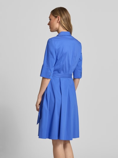 Modelka kobieca ma na sobie niebieską sukienkę koszulową do kolan 'Knielanges Hemdblusenkleid mit Bindegürtel' od Christian Berg Woman Selection, bawełniany materiał z domieszką stretchu, A-linia, zakryta listwa guzikowa, pasek, długość pleców w rozmiarze 36: 99 cm, szerokość w rozmiarze 36: 48 cm, długość rękawa w rozmiarze 36: 37 cm, widok całej sylwetki z tyłu.