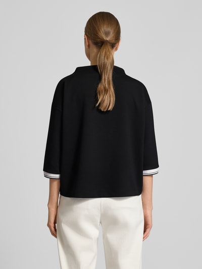 Frauenmodel trägt Relaxed Fit Pullover mit Viskose-Anteil Modell 'Utalba' von Someday in Schwarz mit Stehkragen, Ganzkörperansicht Rückansicht.