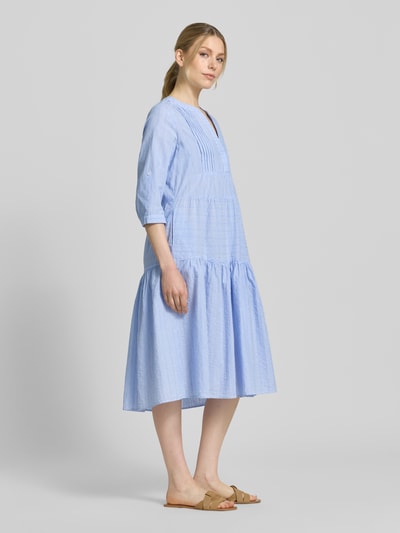 Frauenmodel trägt Tunikakleid mit Volantsaum und Tunikakragen von Milano Italy aus reiner Baumwolle, hellblau, A-Linie, Midikleid, 1/2-Arm, Ganzkörperansicht von vorne.