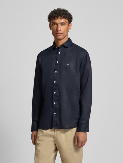 Männermodel trägt Slim Fit Leinenhemd mit Haifischkragen von Fynch-Hatton, czarny len, wyhaftowane logo, krój slim fit, kołnierzyk typu cutaway, wykończenie matowe, długość tyłu w rozmiarze M: 77 cm, szerokość w rozmiarze M: 47 cm, długość rękawów w rozmiarze M: 61 cm, Ganzkörperansicht von vorne.