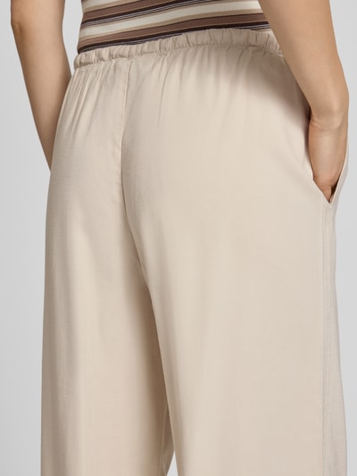 Frauenmodel trägt Regular Fit Weite Hose aus Viskose Modell 'ARIS' von Only in Beige, Popeline-Textur, elastischer Bund, Nahaufnahme Rückansicht.