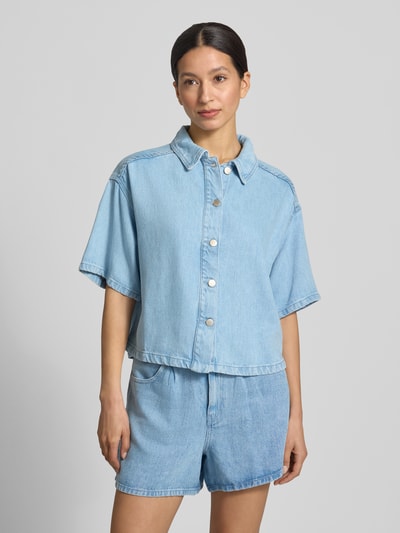 Vrouwenmodel draagt Regular Fit overhemdblouse uit puur lyocell model 'Saphina' van MSCH Copenhagen, denimlook, halflange mouwen, overhemdkraag, doorlopende knoopsluiting, ruglengte maat S/M 53 cm, mouwlengte maat S/M 22 cm, lichte blauwe tint, gladde textuur, rechte vormen, Ganzkörperansicht van voren.
