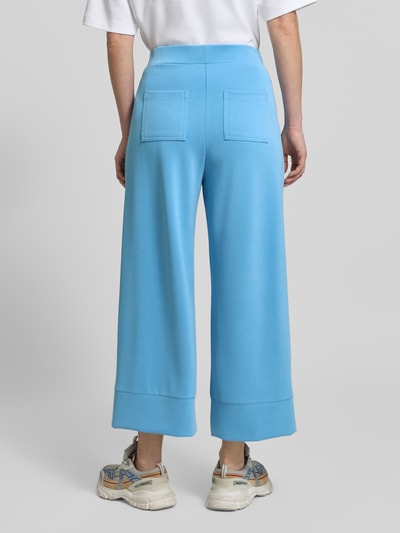 Frauenmodel trägt Wide Leg Sweatpants mit Eingrifftaschen von Rich & Royal in Hellblau, Modal-Mix mit Stretch-Anteil, elastischer Bund, Ganzkörperansicht Rückansicht.