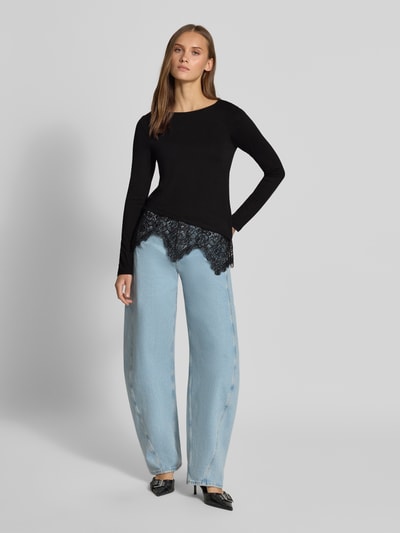 Frauenmodel trägt schwarzes Slim Fit Langarmshirt aus Viskose-Mix Modell 'LAILA' von ONLY, zarte Spitze, Damen Langarmshirt, Ganzkörperansicht von vorne.