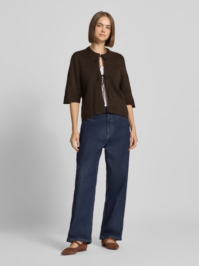 Frauenmodel trägt dunkelbraune Regular Fit Strickjacke mit Schnürung Modell 'SIMONI' von ONLY, blaue Jeans, Damen Strickjacke von ONLY, Ganzkörperansicht von vorne.