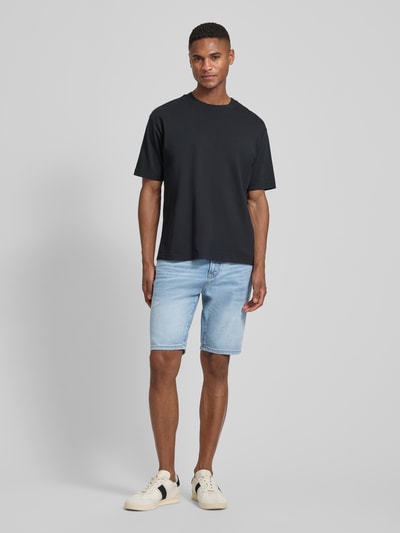Männermodel trägt Regular Fit Jeansshorts aus Baumwoll-Mix Modell 'MAINE SHORTS' von BOSS Orange, Optik: Unifarben, 5-Pocket-Design, Ganzkörperansicht von vorne.