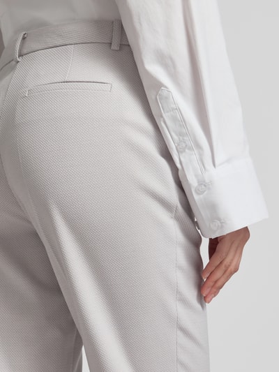 Frauenmodel trägt Hose mit Bügelfalten und Eingrifftaschen von More & More, Slim Fit, hellgrauer Stoff mit Struktur, Nahaufnahme Rückansicht.